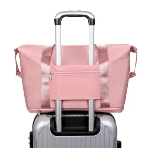 Pink nylon travel duffel bag with luggage trolley sleeve detail for easy suitcase transport.