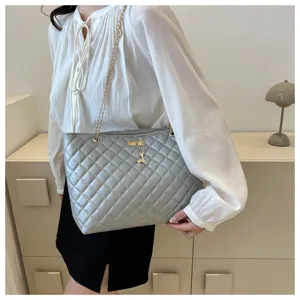 Detailansicht der stilvollen silbernen gesteppten Schultertasche mit goldener Kette.