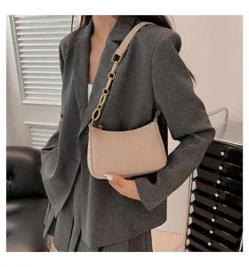 Vista dettagliata di elegante borsa a spalla beige con motivo pietra e catena.