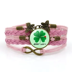 Primo piano del bracciale in pelle intrecciata rosa con cabochon in vetro con trifoglio fortunato.