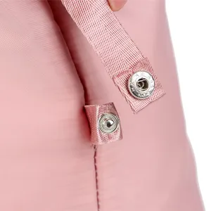 Pink waterproof nylon travel bag detail snap button and fabric strap accessory close up