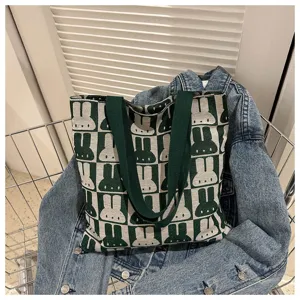 Detail view of a stylish green and beige knitted tote bag with cute rabbit pattern for daily use.