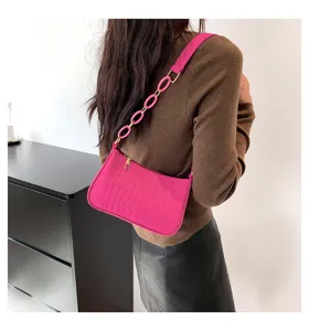 Borsa a tracolla rosa stampa coccodrillo sotto l'ascella con catena indossata da modella.