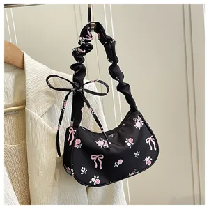 Detailed view of black floral canvas shoulder bag with cute bow and chic scrunchie strap design.