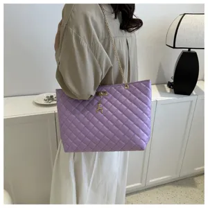 Detailaufnahme der lila gesteppten Schultertasche mit Kettriemen und Hirschanhänger.