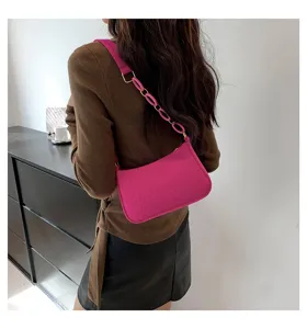 Dettaglio borsa a spalla rosa con stampa coccodrillo e cinturino a catena elegante.