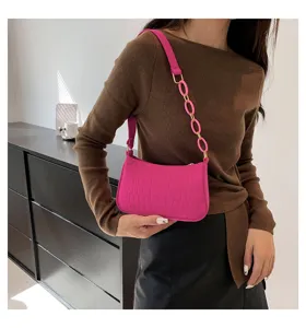 Vista dettagliata di una elegante borsa a spalla rosa con stampa coccodrillo e catena.