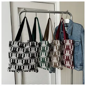Close-up detail of knitted tote bags featuring a cute rabbit pattern design in multiple colors.