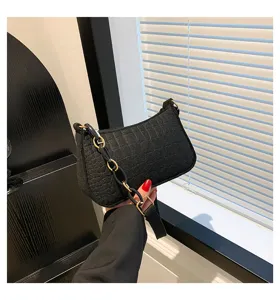 Dettaglio della borsa a spalla in feltro nero con texture in pietra e cinturino a catena.