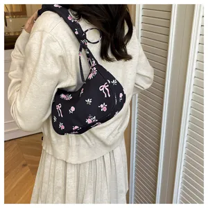 Detailed shot of a sweet black canvas shoulder bag featuring a lovely pink floral and bow pattern.