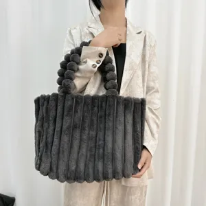 Detailaufnahme einer dunkelgrauen Kunstfell-Tasche mit strukturierten Streifen und Griff.