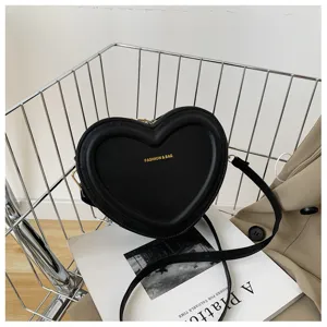 Chic black heart-shaped crossbody bag detail showcasing smooth faux leather and gold lettering.