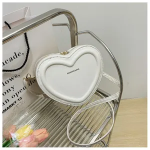 Close-up detail of white heart-shaped crossbody bag featuring smooth leather and stylish strap.