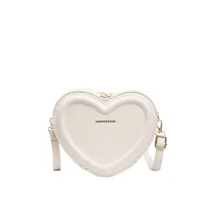 White heart-shaped crossbody bag detail showing embossed front texture and gold hardware.