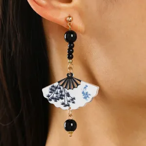 Close-up of a Chinese style fan drop earring with bamboo pattern print on a model