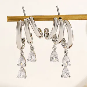 Detailed macro view of silver-tone irregular hoop earrings with pear-cut zircon pendants