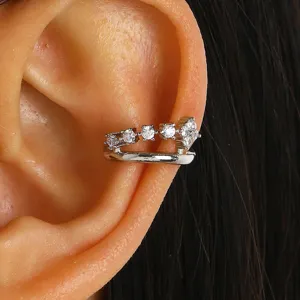 Close-up of a silver hollow ear cuff with zircon crystals on an ear