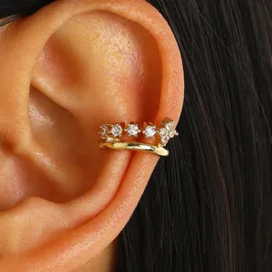 Close-up of a gold-plated ear cuff featuring sparkling cubic zirconia stones on a model's ear.
