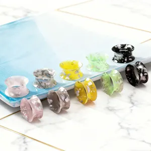 Detailed close-up view of colorful splatter painted ear tunnels and plugs body jewelry.