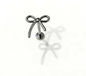 Dettaglio in primo piano del gioiello da piercing labret in titanio a forma di fiocco.