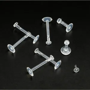 Detalle de piercings de nariz y labret transparentes de bioplástico, joyería corporal flexible.