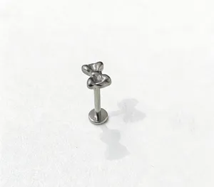 Primo piano dettagliato del piercing labret in titanio con design a fiocco, finitura argento.