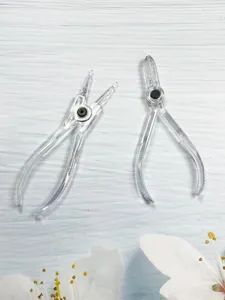 Detailed close-up of clear acrylic body piercing pliers and closing tools, transparent design.