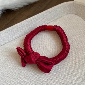 Red fabric bow hair tie detail, elegant elastic hair ring close up view for daily styling.