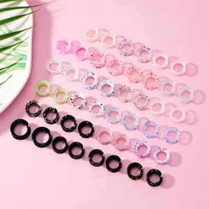 Detailansicht von bunten Splatter- und schwarzen Ohrdehnern, Körperpiercing Schmuck.