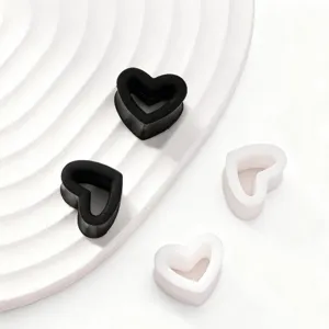 Gros plan d'écarteurs d'oreilles en silicone cœur noir et blanc, bijou de piercing élégant.
