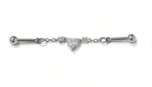 Close-up detail of industrial piercing barbell with heart crystal charm and delicate chains.