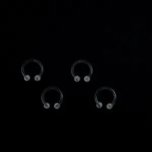 Clear acrylic horseshoe piercing rings, detailed view of four body jewelry pieces.