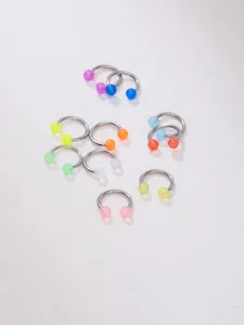 Close-up detail of colorful acrylic horseshoe rings and body piercing jewelry items.