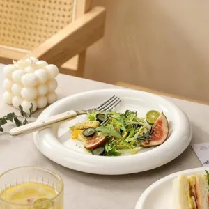 Assiette plate en céramique blanche, vaisselle moderne et minimaliste pour salade et steak.