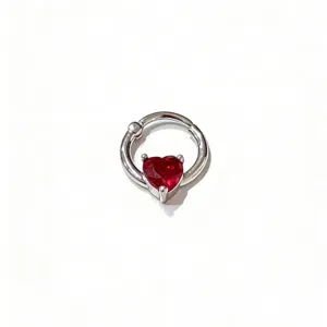 Detailed shot of a silver clicker septum ring with a shiny red heart gemstone accent.