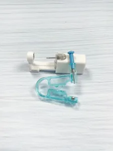 Disposable body piercing tool detail, transparent piercing clamp and auxiliary tool close-up.