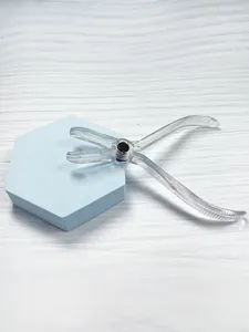 Detail shot of transparent acrylic body piercing closing pliers on blue hexagonal prop.