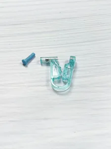 Closeup detail view of the transparent body piercing auxiliary tool and blue pin accessory.