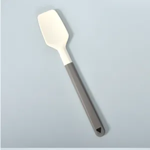 Silicone spatula detail view showing white head and grey handle with hanging hole for baking.