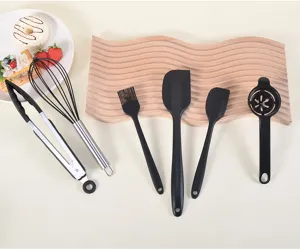 Detail view of the black silicone kitchen utensil set, showing spatulas, whisk, and food tongs.