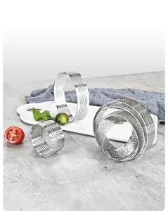 Detailed view of perforated stainless steel tart rings and mousse cake molds for baking.