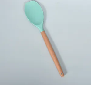 Vista detallada espátula de silicona, cabeza verde menta y mango de madera para cocina.