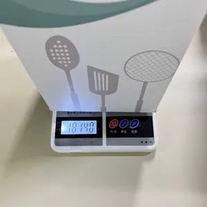Detail view of the kitchen utensil set packaging being weighed on an electronic scale.