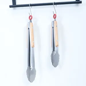 Stainless steel food tongs with wooden handle hanging display for outdoor BBQ and kitchen use