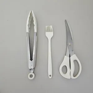 Detailed view of kitchen barbecue tools including stainless tongs brush and scissors set.