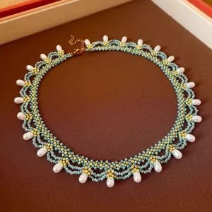 Handgemaakte kralenketting detail, met turquoise zaadkralen, goudkleurige accents en witte druppelparels.