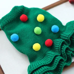 Dettaglio ravvicinato del maglione lavorato a maglia verde con ponpon colorati per cani.