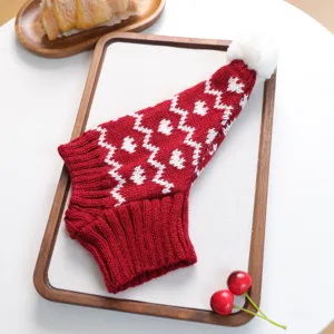 Détail de bonnet de Noël tricoté rouge et blanc pour animal, adorable design pointu avec pompon doux.