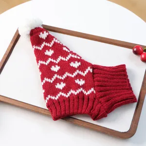 Vue détaillée d'un bonnet de noël tricoté rouge et blanc pour animal avec pompon.