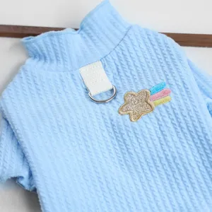 Primo piano di un grazioso maglione per cani blu chiaro con anello di trazione e stella.